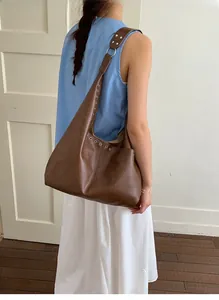 Nahaufnahme der braunen Vintage Hobo-Tasche mit silbernen Ösen und breitem Gurt