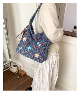 Dettaglio della borsa tote in denim blu con fiori 3D e decorazioni con fiocchi