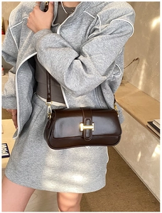 Detailed view of the dark brown shiny leather finish and gold H-buckle of the shoulder bag