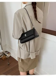 Close-up of black leather bag with silver rivets and metal chain shoulder strap detail