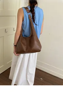 Braune Shopper-Tasche aus Leder mit Metallösen, seitliche Ansicht an der Schulter