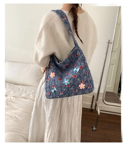 Dettaglio della borsa tote in denim blu con motivi a quadretti rossi e fiocchi floreali