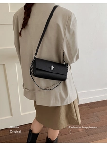 Detail of black lychee grain crossbody bag with silver twist lock and chain strap