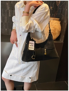 Détail du sac porté épaule en cuir noir mat avec fermeture dorée et étiquette