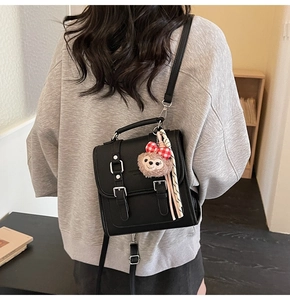 Detailed view of black textured square bag with silver buckle and plush bear charm