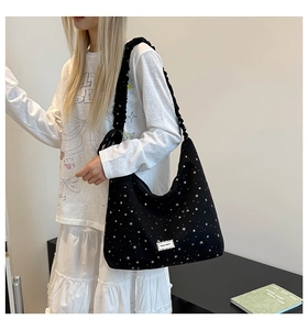 Detail of black polka dot canvas tote bag featuring star patterns and ruched wide shoulder strap