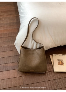 Detailed view of dark brown leather tote bag texture with elegant gold adjustment buckles