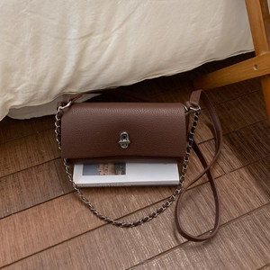 Detail of brown litchi pattern leather bag with silver chain strap and metal lock