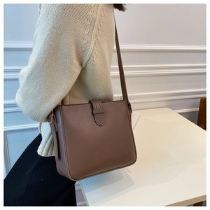 Detailansicht der braunen Leder-Beuteltasche an einem Model mit elegantem Wohn-Hintergrund