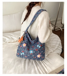Dettaglio borsa tote in denim blu con toppe a quadretti, fiori 3D e ciondolo a cane