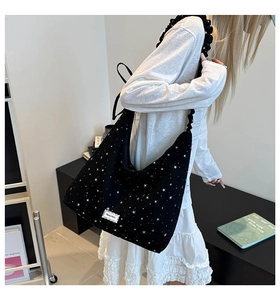 Detail of black canvas shoulder bag featuring white star pattern and lace label trim