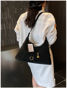 Sac hobo noir en forme de lune avec détails dorés et bandoulière en cuir minimaliste