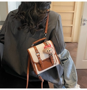 Detail of vintage crossbody bag with contrast leather stitching and plush bear charm