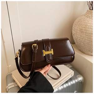 Detail of dark brown baguette bag featuring a gold buckle and adjustable leather strap