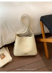 Detail of cream vintage tote with crinkled leather texture and gold metal bar accents