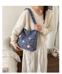 Dettaglio della borsa tote in denim blu con motivo a quadri rossi e fiori 3D con fiocchi