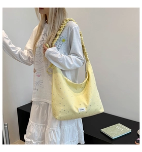 Detail of light yellow canvas tote bag featuring silver star sequins and ruched handle