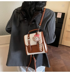 Detail of caramel and white textured faux leather square bag with decorative buckles