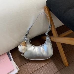 Detailansicht der silbernen Mondsichel-Tasche mit Metallic-Finish und Plüsch-Anhänger