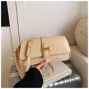 Detail of cream PU leather shoulder bag with gold H-buckle shown in a lifestyle setting