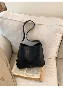 Detail of vintage cracked leather texture and golden brand plaque on black tote bag