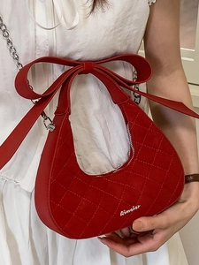 Red crescent shoulder bag with quilted pattern, bow detail, and silver chain strap