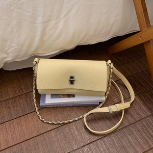 Detail of creamy yellow satchel showing pebbled leather texture and silver twist lock