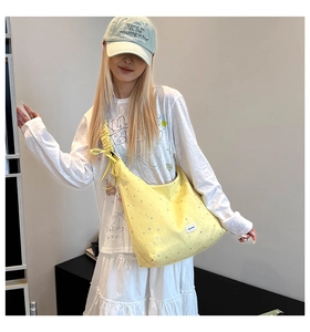 Detail of yellow canvas tote bag with star print and ruffled bow shoulder strap