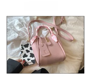 Dettaglio della trama in pelle litchi rosa e sciarpa di seta decorativa sulla borsa