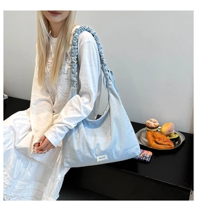 Macro detail of light blue canvas tote bag with star print and ruffled shoulder strap
