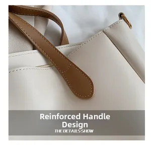Detail view of the reinforced handle stitching on this cream leather tote bag