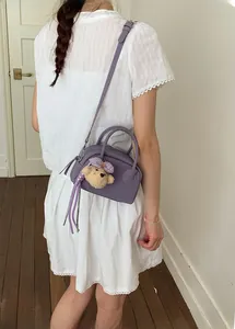 Detail of light purple bowling bag with cute brown plush bear charm and crossbody strap