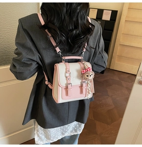 Detail of pink and white square crossbody bag with a cute plush bear charm on a model