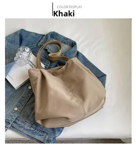 Detail view of khaki nylon tote bag with leather logo tag and fabric handles