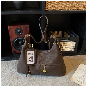 Détail du sac Hobo marron foncé avec poche zippée, finitions dorées et pendentif de mode