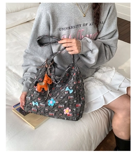 Dettaglio della borsa tote in tweed grigio con fiori 3D e ciondolo a forma di cavallo