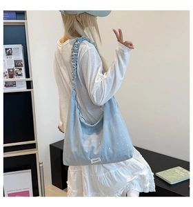 Detail of light blue hobo bag with silver stars and ruffled shoulder strap
