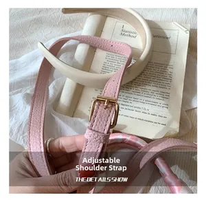 Dettaglio tracolla regolabile in pelle rosa con fibbia dorata e fascia beige