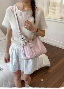 Pink matte faux leather crossbody bag with cute white bear charm shown on a model