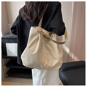 Back view of model wearing a large cream nylon tote bag with wide shoulder strap