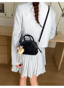 Detail of black bowling handbag with textured leather and a cute plush bear pendant