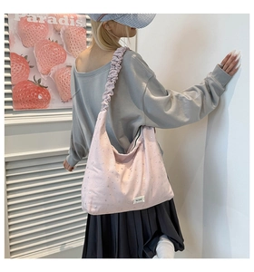 Pink canvas tote bag with star patterns and pleated shoulder strap shown on model