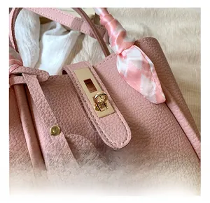 Dettaglio borsa a secchiello in pelle rosa con chiusura dorata e sciarpa di seta