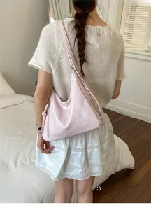 Detail of light pink PU leather hobo bag featuring side tassel and minimalist branding