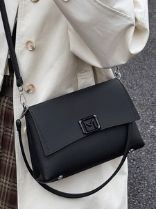 French style black flap shoulder bag with metal M logo shown on a fashion model