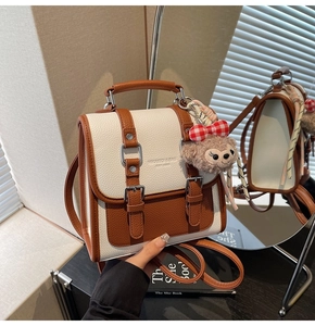 Detail of white and brown textured leather crossbody bag with cute plush bear charm