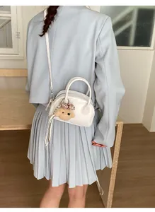 Back view of a model wearing a white mini bowling bag with a plush dog charm