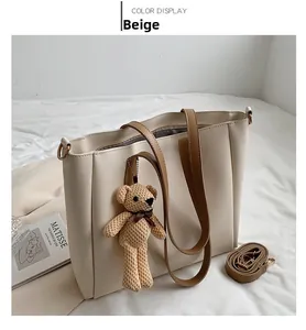 Detail of beige tote bag with dark brown handles and a cute knit bear charm attachment