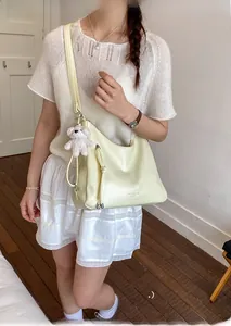 Close-up of beige textured leather tote bag with cute bear charm worn by a model
