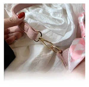 Dettaglio borsa a secchiello in pelle rosa con ganci dorati e sciarpa di seta